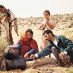 Nomads cooking on barrel stove in desert